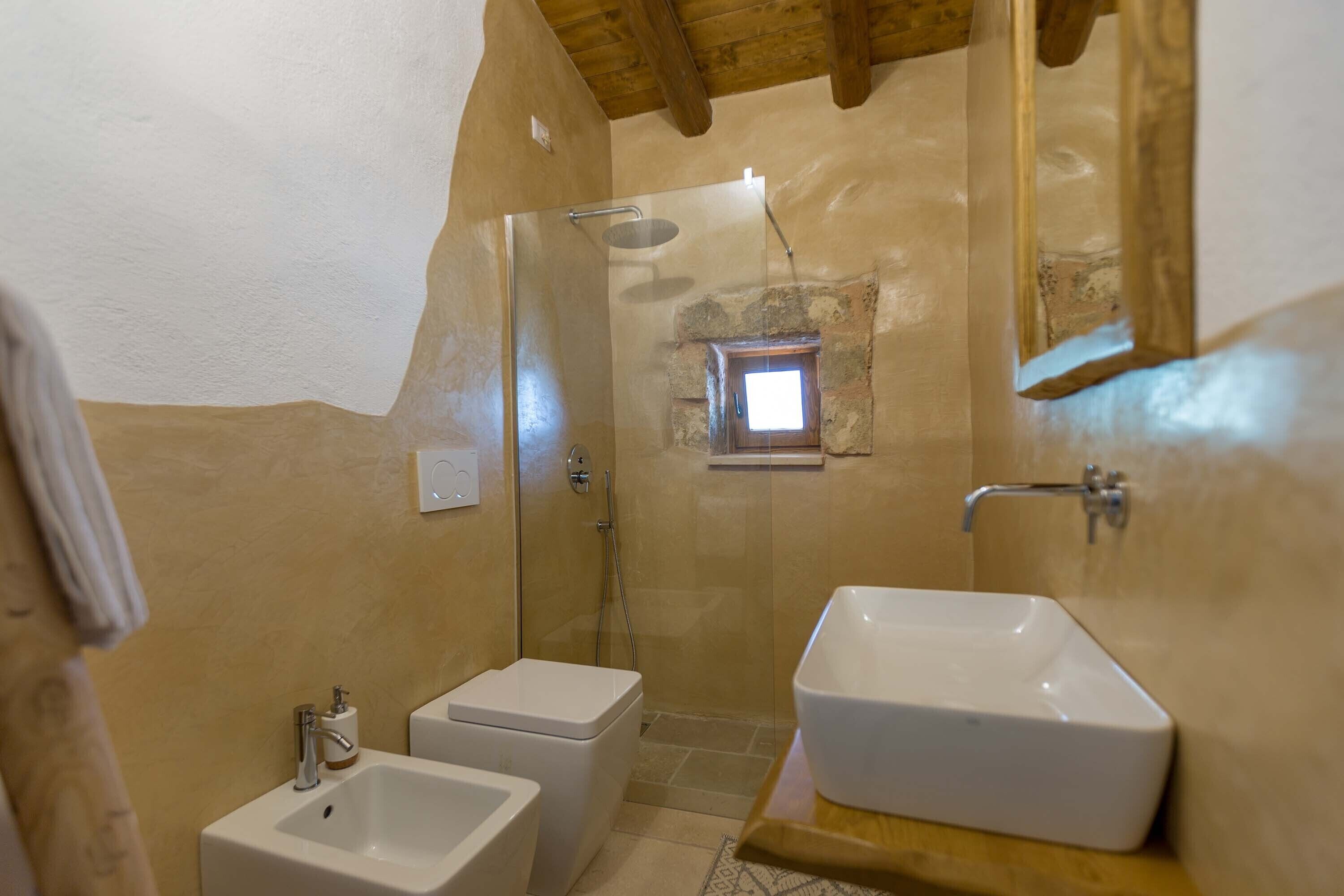 A bathroom with a shower, two sinks, and a small window.