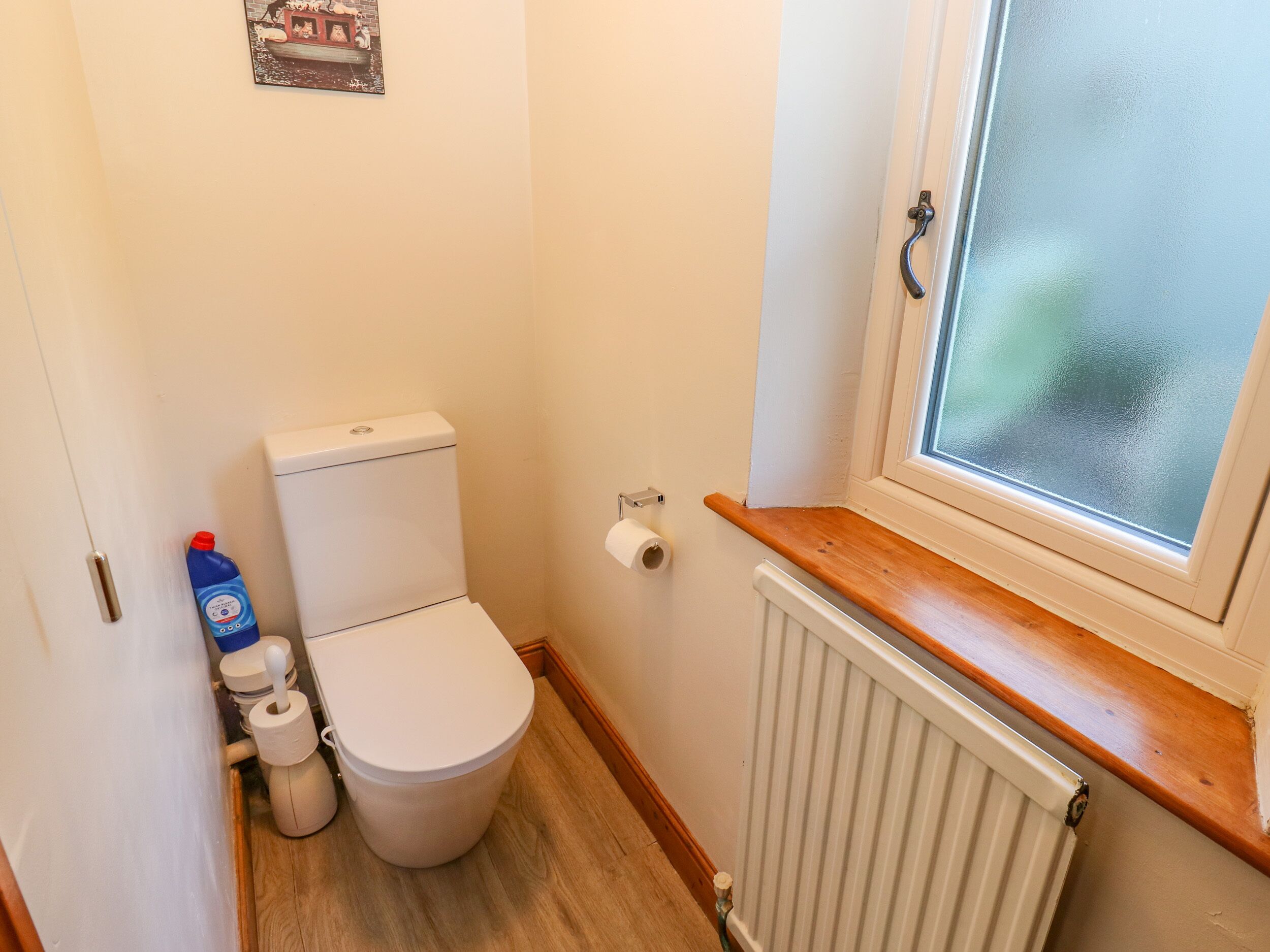 Une petite salle de bain compacte, équipée de toilettes, d’un radiateur et d’une fenêtre.