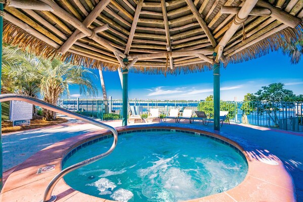 A hot tub area with a wooden canopy, lounge chairs, and a pool in the background. - Caribe The Resort D614 3 Bedroom Condo (Orange Beach)