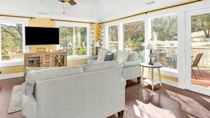 A spacious living room with a large gray sectional sofa, a flat-screen TV mounted on the wall, and a wooden cabinet with drawers. - Awesome Views, Game Room, Hot Tub and More! (Oakhurst)