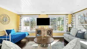 A bright living room with a bed, a sofa, a TV, and a wooden cabinet. - Awesome Views, Game Room, Hot Tub and More! (Oakhurst)