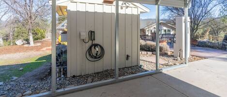 A covered outdoor area with a utility box and a coiled cable on a wooden fence.