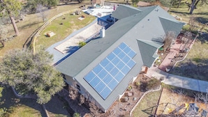 A house with a large solar panel array on the roof, a covered patio, and a fenced yard. - Awesome Views, Game Room, Hot Tub and More! (Oakhurst)