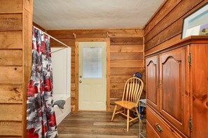 Interior de una cabaña de madera con una puerta, una silla y un armario.