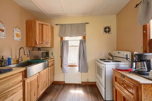 Una cocina compacta con armarios de madera, microondas, estufa y cafetera.