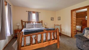 A bedroom with a wooden bed frame, a nightstand, a chair, and a wooden wardrobe.