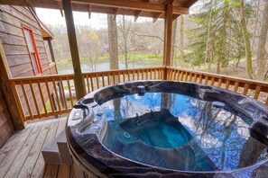 Un jacuzzi en una terraza de madera con vistas a árboles y un cuerpo de agua.