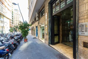 A street with parked motorcycles, a potted tree, and a building with large windows and a door. - Toledo Bright Apartment by Wonderful Italy (Naples)