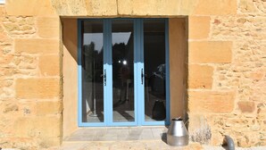 Een stenen gebouw met een deur van glas met blauwe lijst en een metalen emmer op de grond.