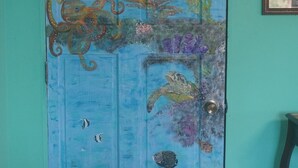 A blue door with an ocean-themed mural, including fish, coral, and an octopus. - Kayak, Snorkel, Dive Waterfront 2BR 2BA  A/C
Beautiful Quiet Caribe bight w/pool (Jonesville Point)