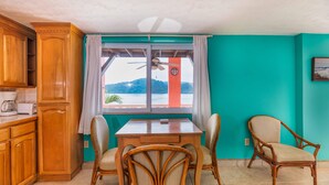 A kitchen with wooden cabinets, a dining table with chairs, a window with a view of hills, and a ceiling fan. - Kayak, Snorkel, Dive Waterfront 2BR 2BA  A/C
Beautiful Quiet Caribe bight w/pool (Jonesville Point)