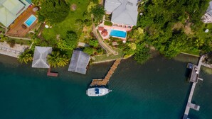 An aerial view of a residential area with a dock, a boat, and a swimming pool. - Kayak, Snorkel, Dive Waterfront 2BR 2BA  A/C
Beautiful Quiet Caribe bight w/pool (Jonesville Point)