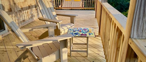 A wooden deck with Adirondack chairs and a table with a board game.