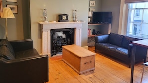 A living room with a fireplace, leather sofa, wooden coffee table, and a television. - Captivating 2-bed Apartment in Winchester (Winchester)