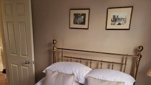 A bed with a white quilt and four pillows, a gold-framed headboard, and two framed pictures on the wall. - Captivating 2-bed Apartment in Winchester (Winchester)