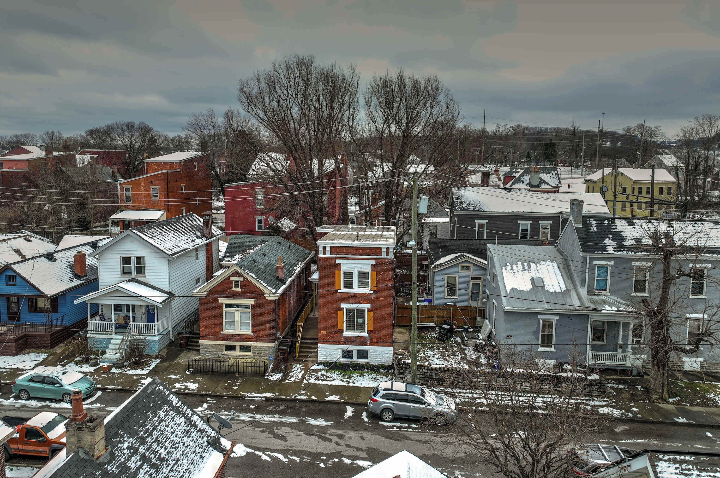 A residential area with houses, some with snow on the roofs and ground.