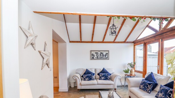 Un salon avec un canapé, un fauteuil et une table basse. Des décorations en forme d’étoiles ornent le mur, et un tableau encadré est accroché au-dessus du canapé.