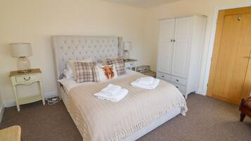 A neatly arranged bedroom with a large bed, a wardrobe, and a bedside table with a lamp.