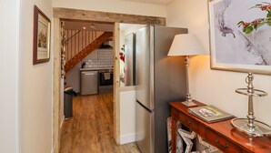Une cuisine équipée d’un réfrigérateur en acier inoxydable, dotée d’un plancher en bois et d’un escalier en bois menant à une mezzanine.