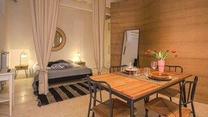 Une chambre moderne comprenant un lit, des tables de chevet, un bureau et un coin repas avec une table et des chaises.