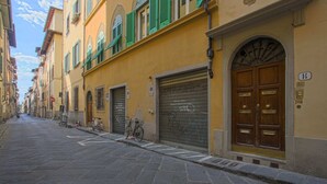 Une rue étroite bordée de bâtiments historiques, aux volets clos, et où un vélo est garé près du trottoir.