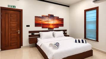 Habitación de hotel con cama, mesita de noche, una obra de arte colgada en la pared, señal de salida y ventana con persianas.