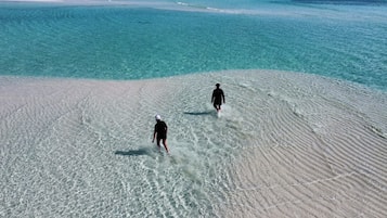 Una playa con dos personas caminando sobre la arena.