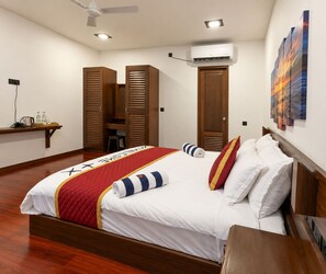 A hotel room with a bed, wooden wardrobe, an air conditioning unit, and a painting on the wall. - Suncoral Maldives (Kondey)