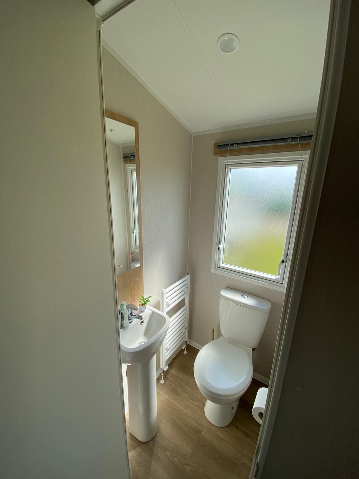 A compact bathroom with a white sink, toilet, and radiator.