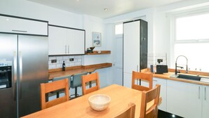 Una cucina moderna con un tavolo da pranzo, sedie, un frigorifero, un lavello e una finestra.