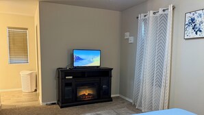 A bedroom with a bed, a fireplace, a television on a stand, and a window with blinds. - Beautiful and cozy home, perfect for long stay (Alamogordo)