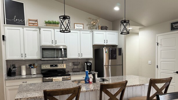 A modern kitchen with white cabinets, stainless steel appliances, and a granite countertop. - Beautiful and cozy home, perfect for long stay (Alamogordo)