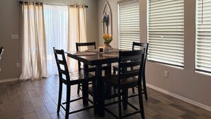 A dining area with a table and chairs, a vase with flowers, and a wall-mounted sign. - Beautiful and cozy home, perfect for long stay (Alamogordo)