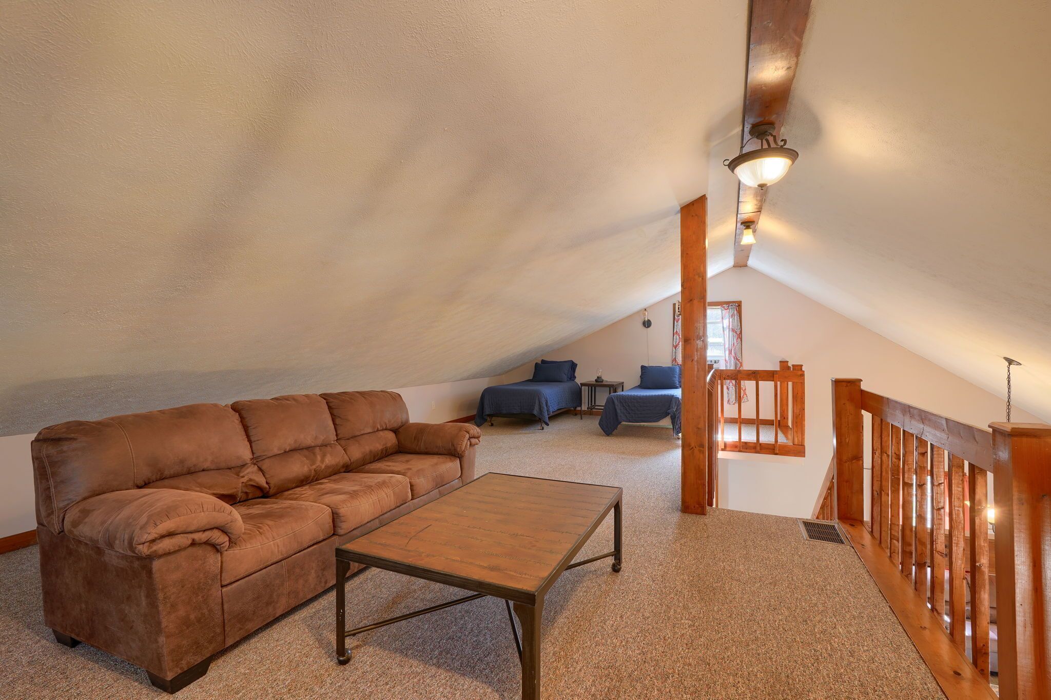 Ein gemütliches Schlafzimmer im Loft-Stil mit einer braunen Ledersofa, einem Holztisch und einer Treppe mit Holzgeländern.