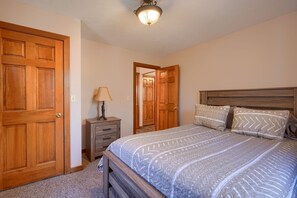 A bedroom with a large bed, wooden headboard, and two doors.