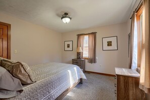 A bedroom with a bed, a nightstand, a lamp, and two framed pictures on the wall.
