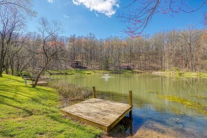 A serene lakeside park with a wooden dock, benches, and a small building in the background.