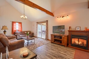 A living room with a fireplace, sofa, coffee table, and a view of the outdoors through a sliding glass door.