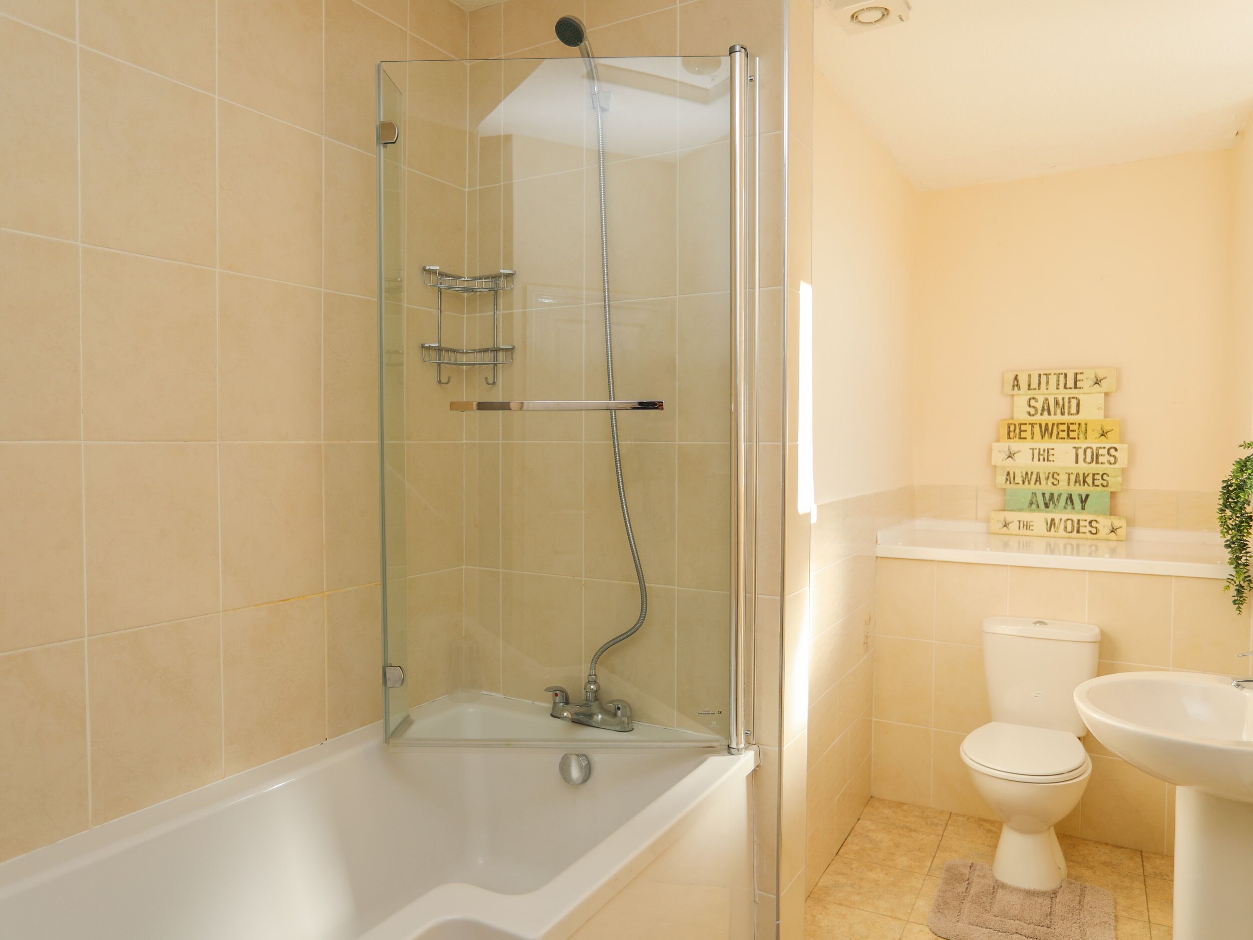 A bathroom with a glass-enclosed shower, a white bathtub, a toilet, and a sink.