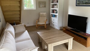 Ett mysigt vardagsrum med en soffa, ett träbord, en bokhylla och en tv.