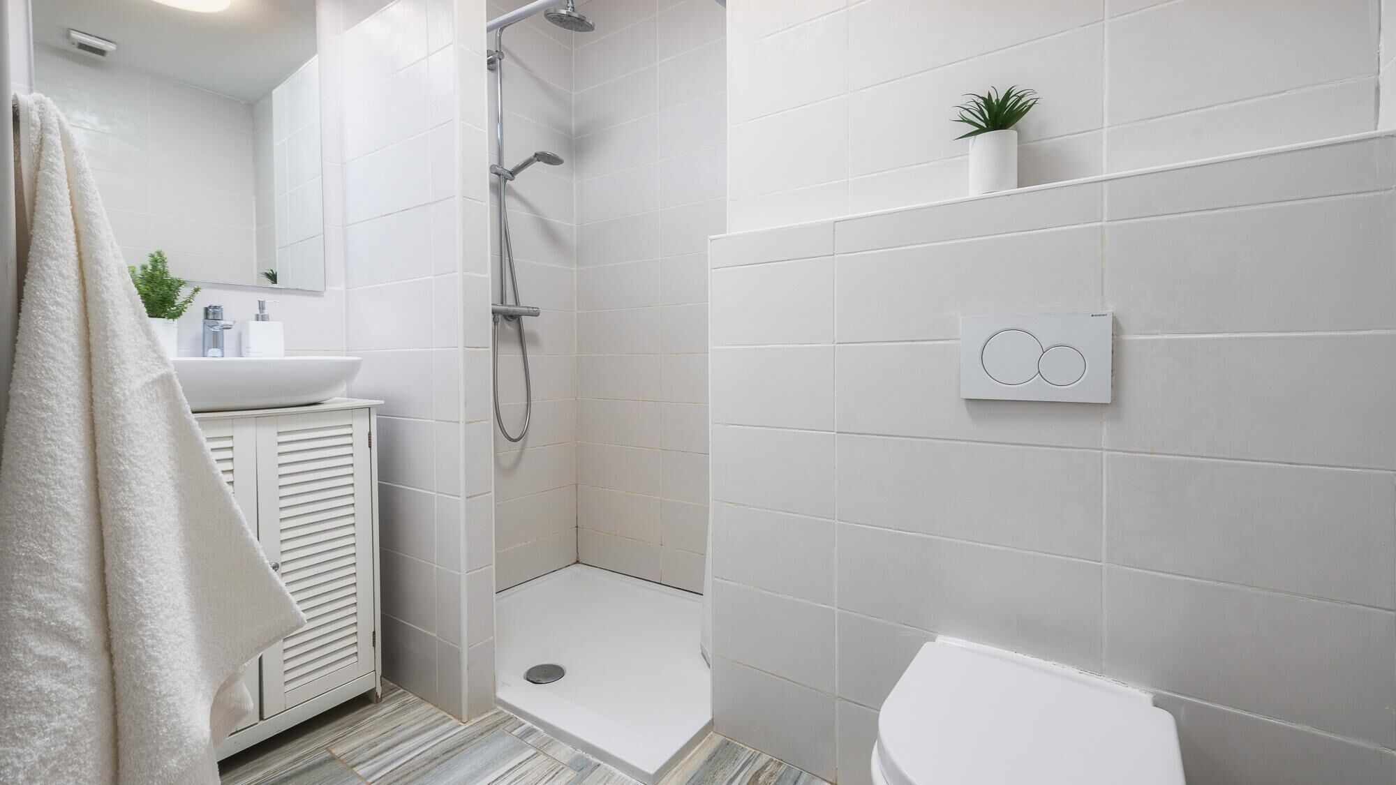 A modern bathroom with a shower, toilet, and sink.
