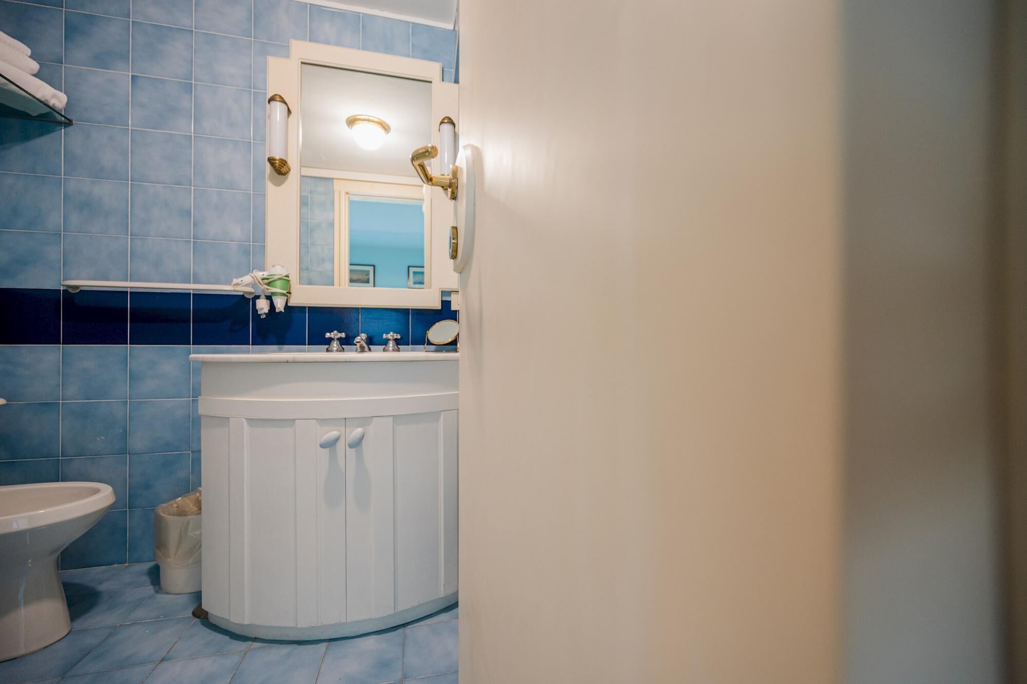 A bathroom with a white sink, a mirror above it, and a toilet.