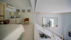 Una camera d'albergo con un letto, una scrivania con una lampada, una sedia, uno specchio e una scala.