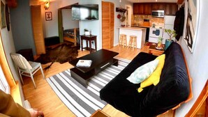 Un espace de vie compact comprenant un canapé, une table basse et un coin cuisine équipé d’un four à micro-ondes et d’une cuisinière.