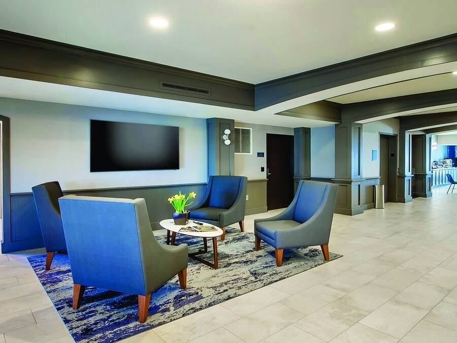 A modern lobby with seating, a flat-screen TV, vending machines, and a view into the dining area.