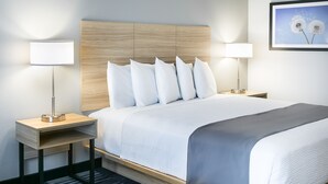 A hotel room with a large bed, two bedside tables, and a headboard. - Winds Hotel At Crosswinds Casino (Park City)
