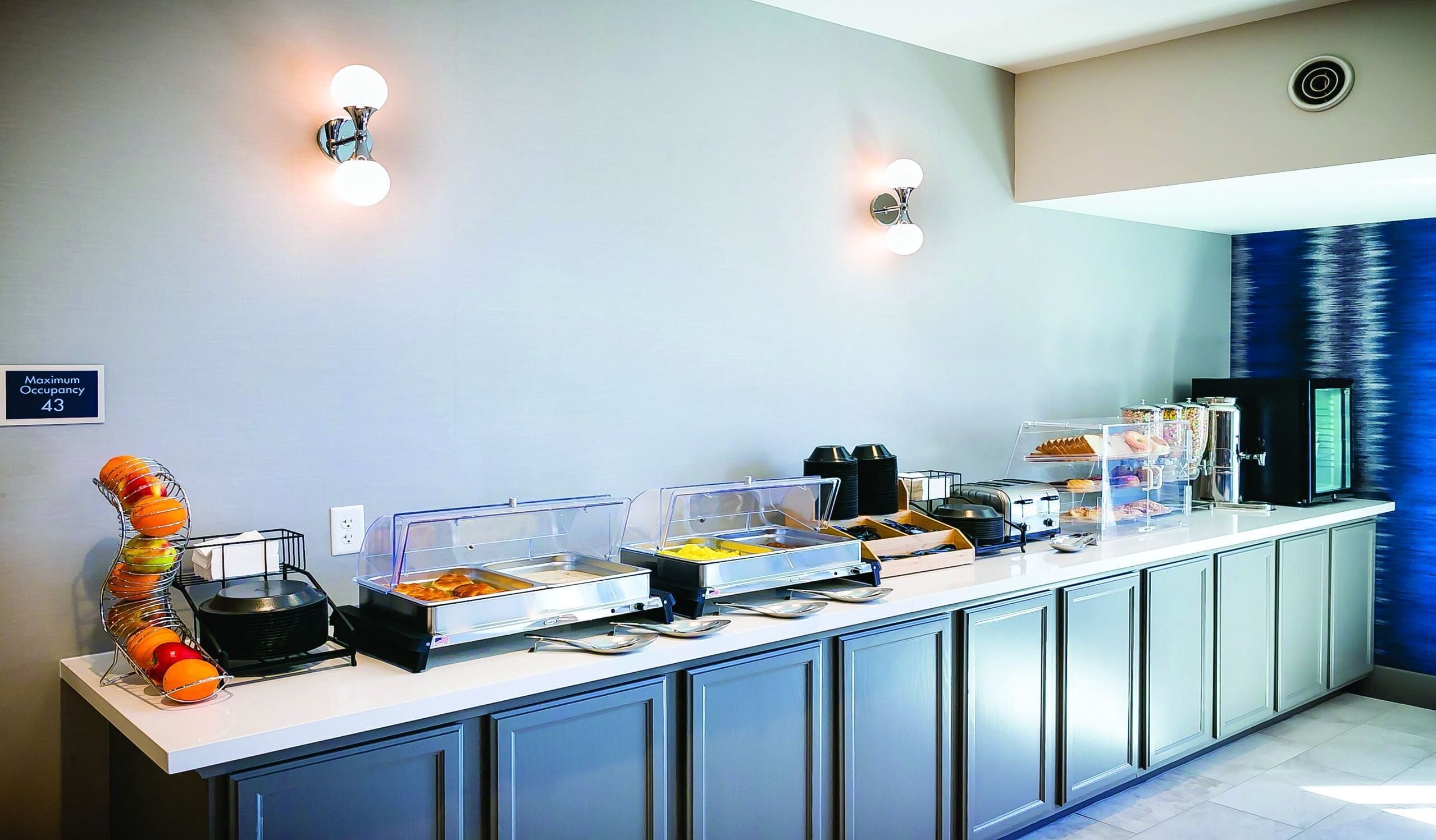 Morgenmadsbuffet med forskellige madmuligheder, et frugtudvalg og en kaffemaskine.