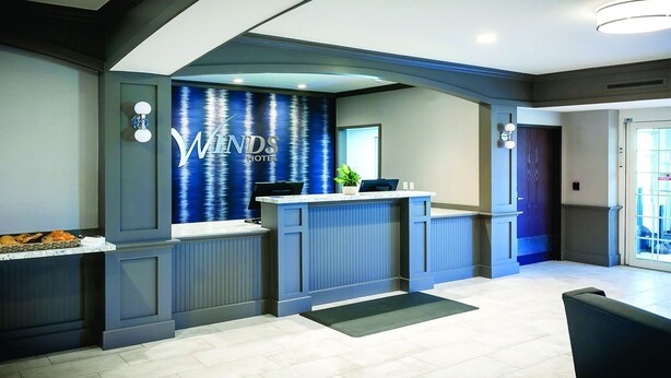 A reception area with a blue wall, a reception desk, and a plant. - Winds Hotel At Crosswinds Casino (Park City)
