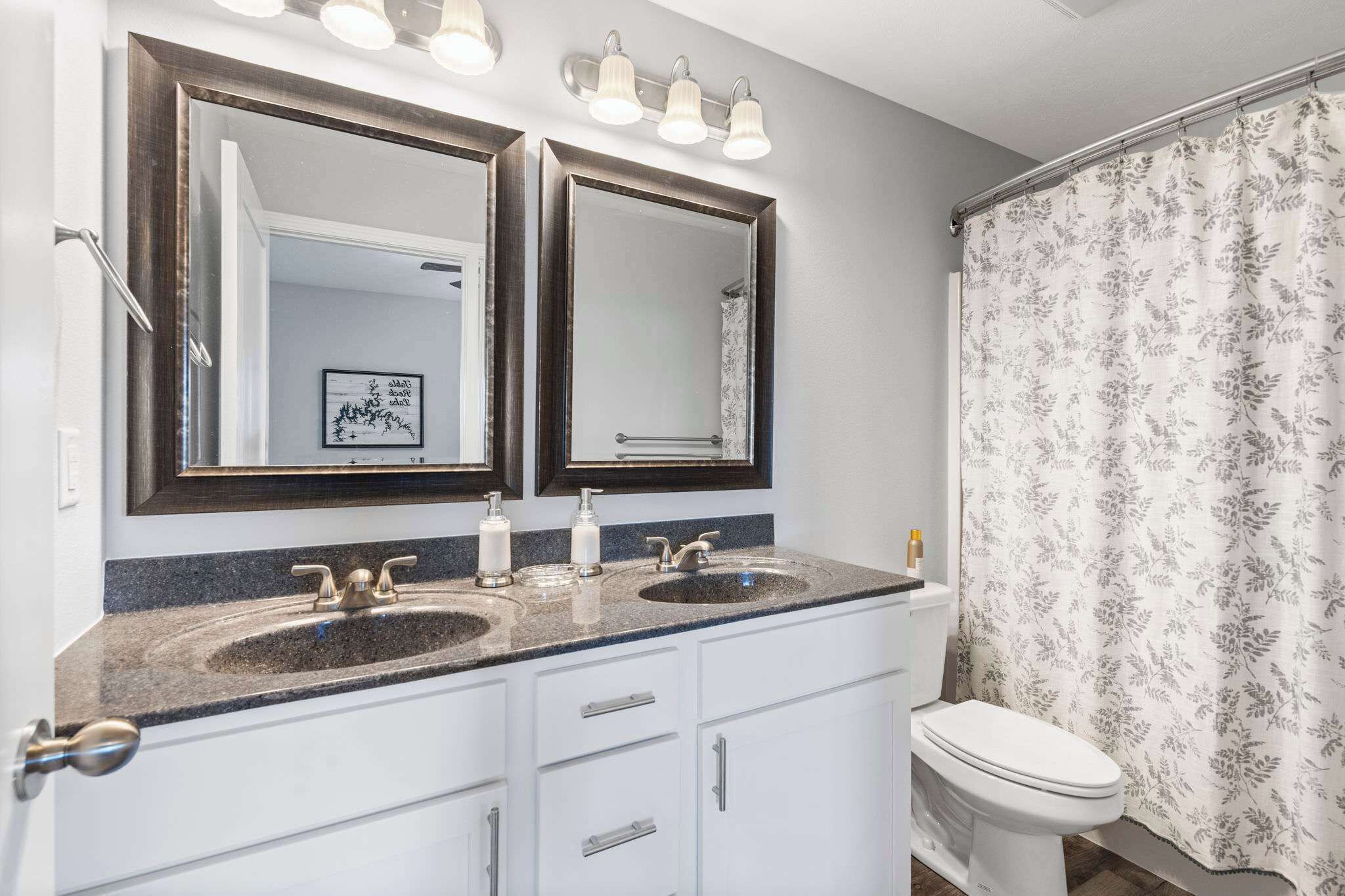A bathroom with two sinks, a toilet, and a shower curtain.
