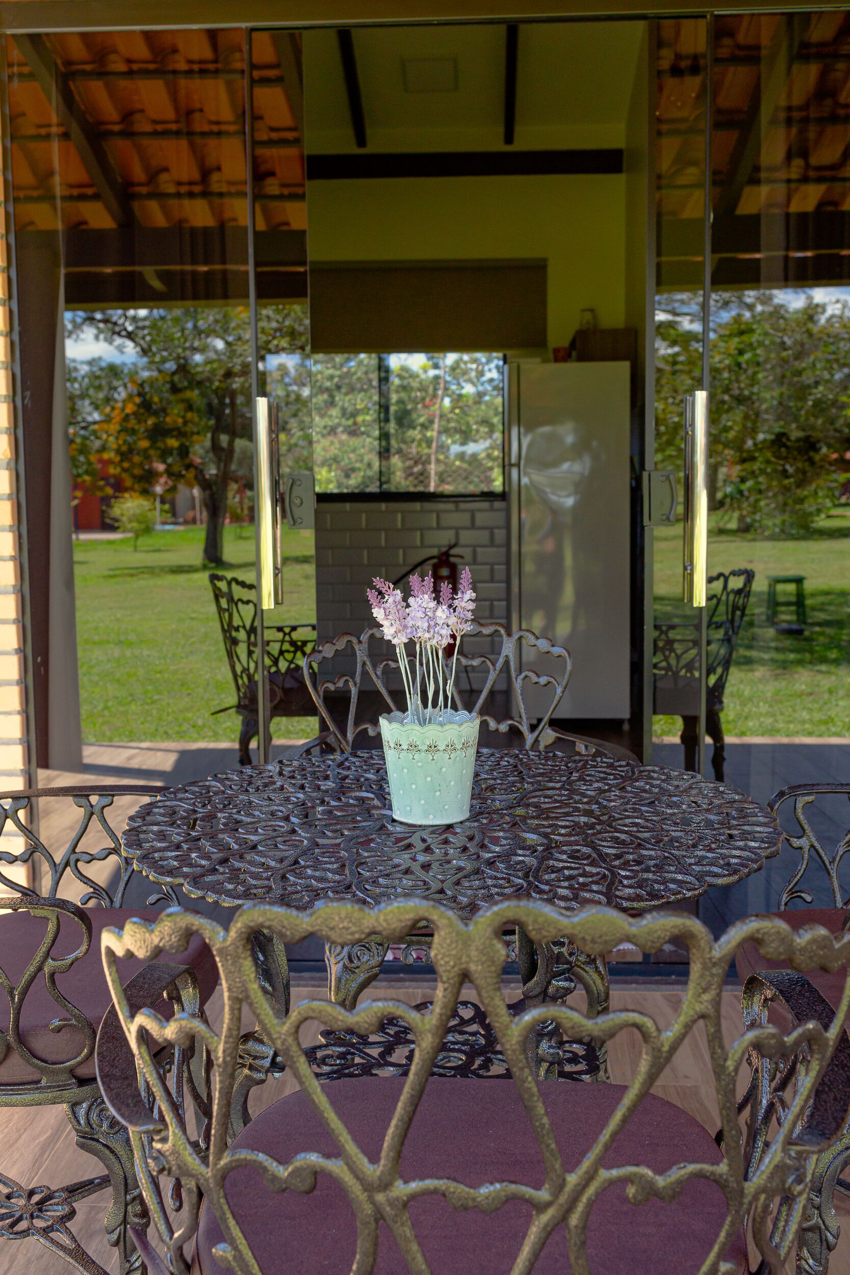 Un patio con una mesa redonda, sillas y un florero decorativo.